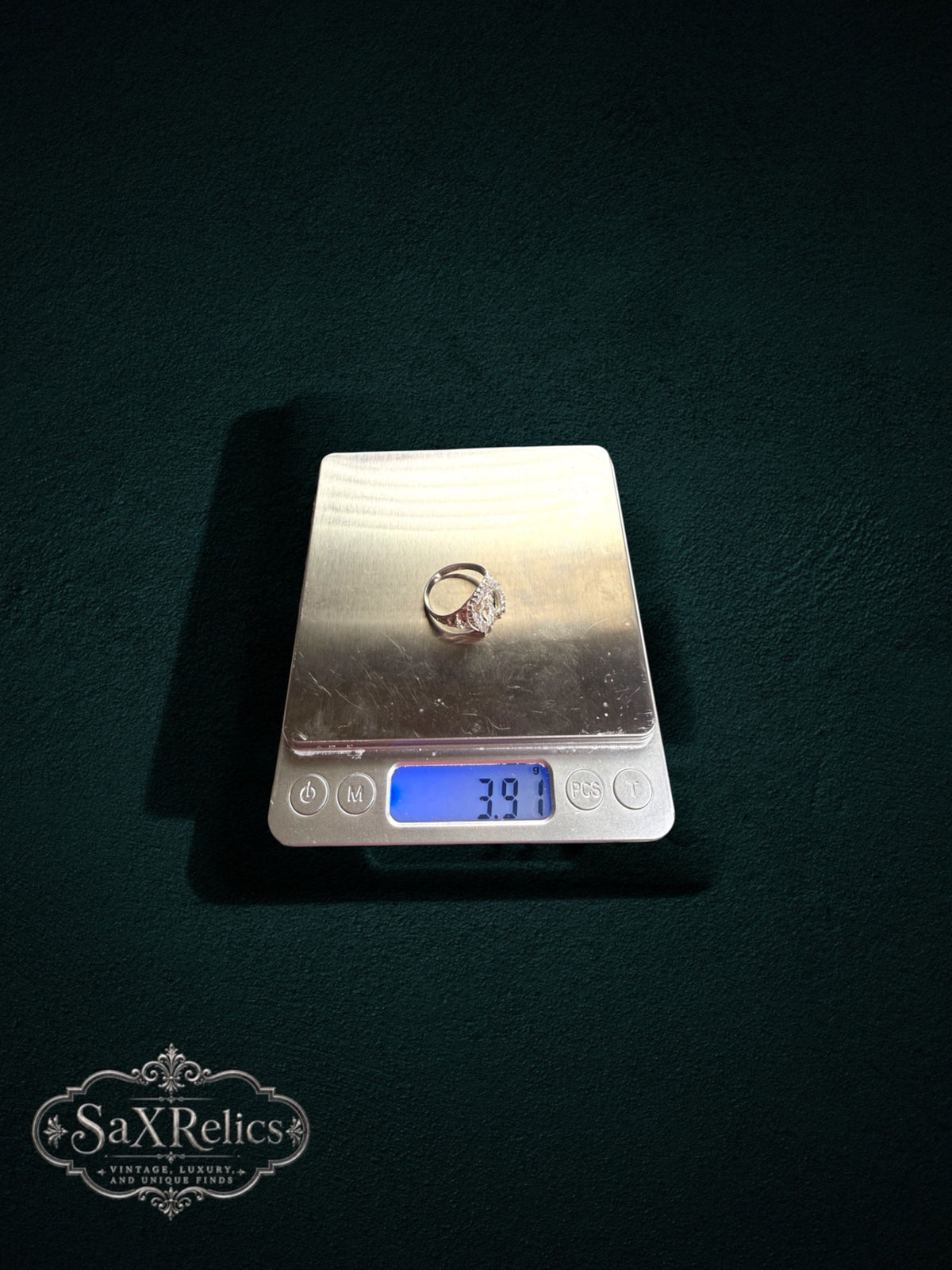 My Store SAXRelics religious ring with Virgin Mary and horseshoe design on a digital scale weighing 3.91 grams.