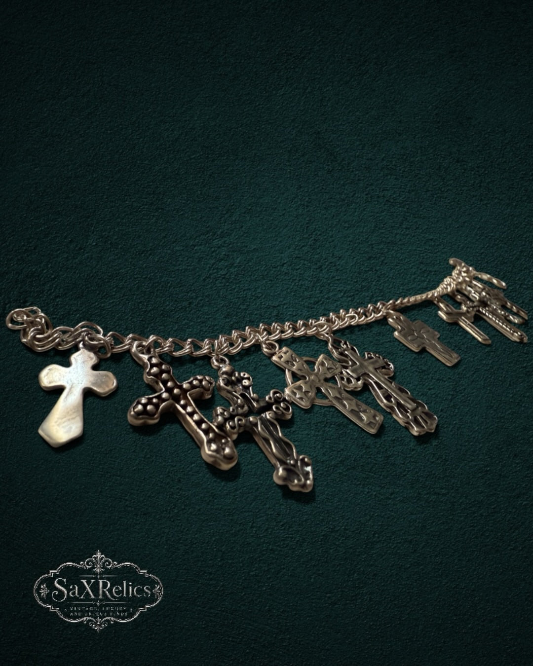My Store SaxRelics silver-tone charm bracelet featuring various intricate cross pendants on a textured dark background