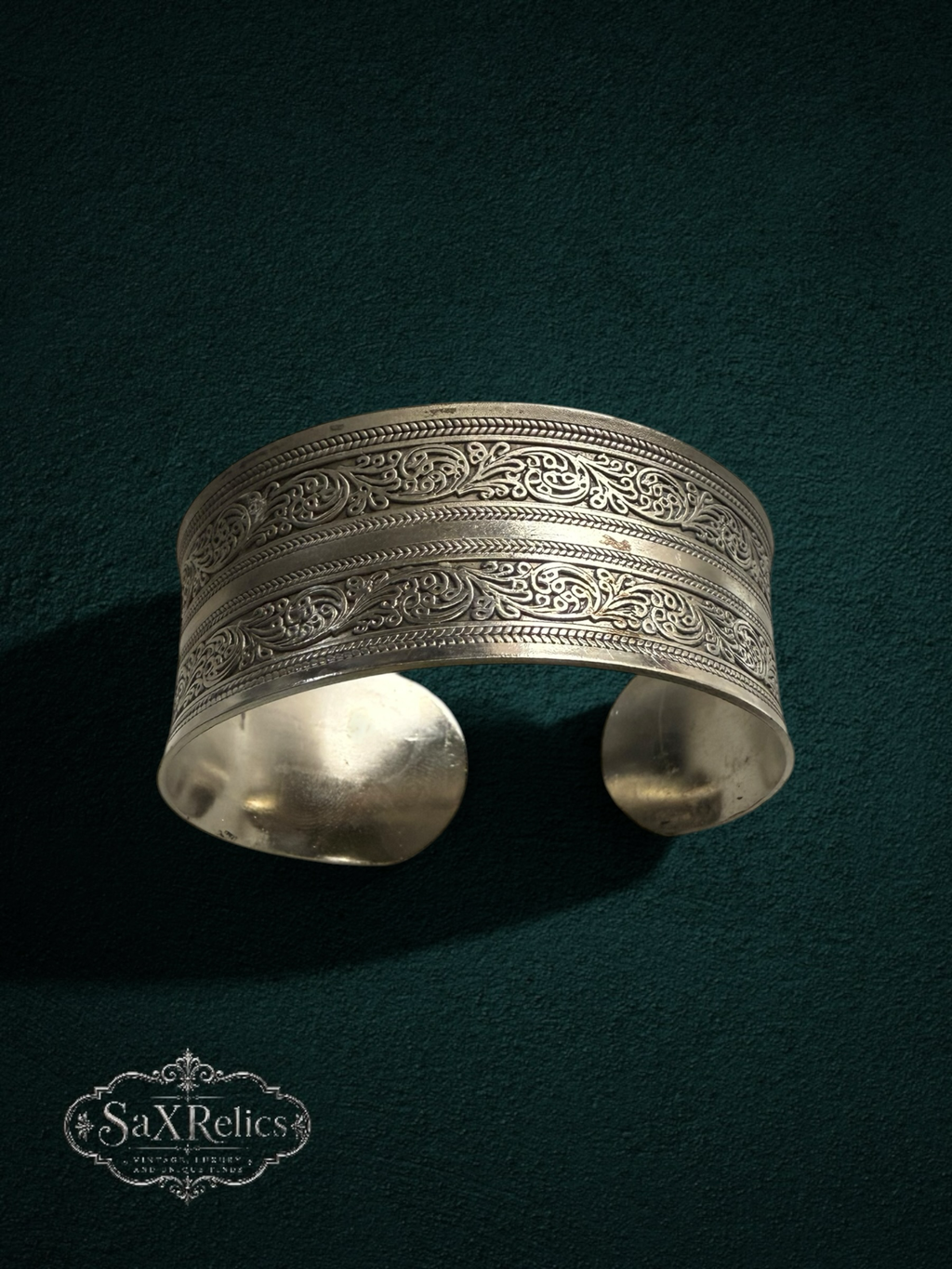 My Store SaXRelics silver wide cuff bracelet with intricate floral engravings and an adjustable open-back design.