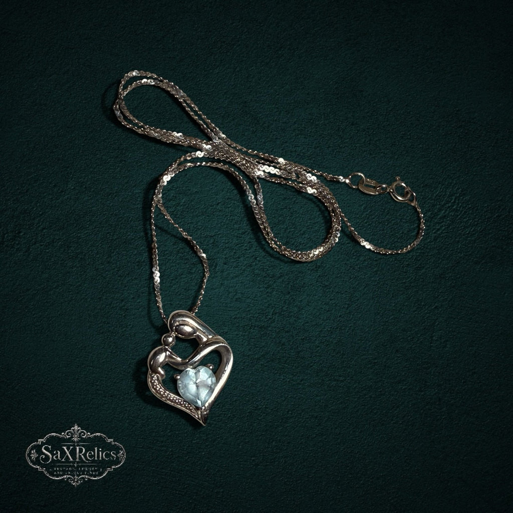 My Store SAXRelics sterling silver mother and child heart pendant necklace with a light blue heart-cut gemstone.