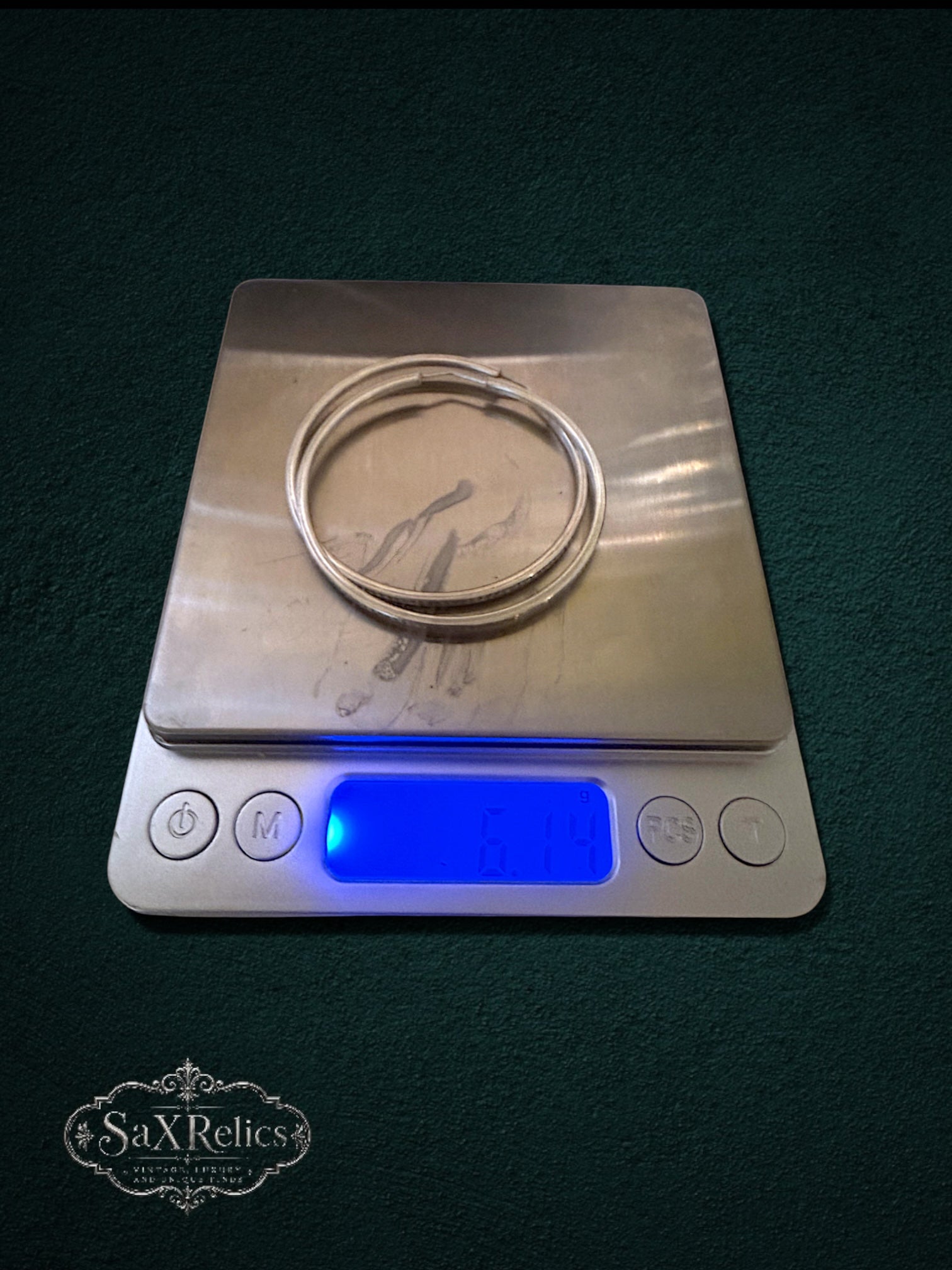 My Store SaxRelics large sterling silver hoop earrings with textured edges resting on a digital scale showing 6.14g