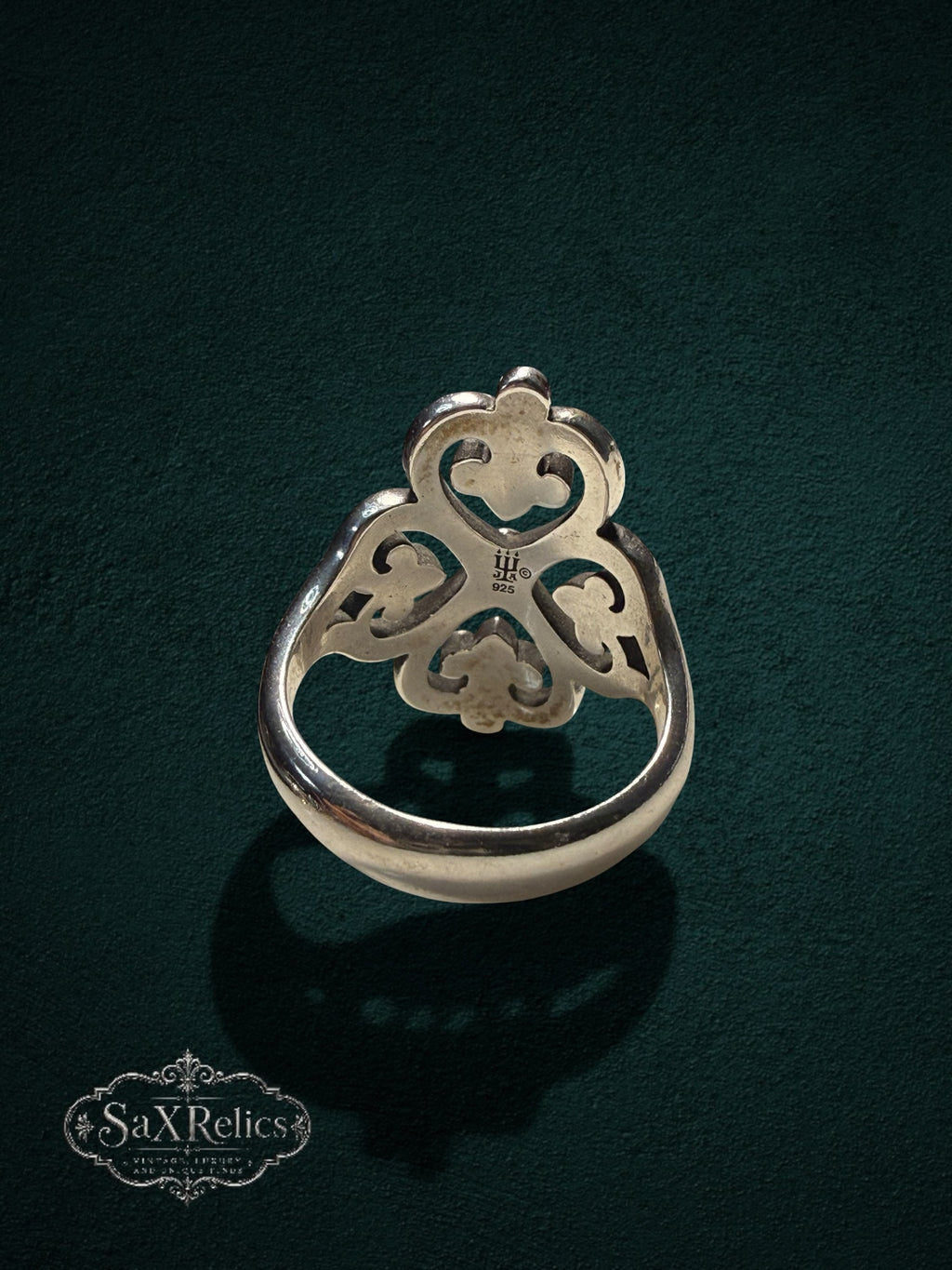 My Store SAXRelics sterling silver ring featuring an ornate quatrefoil filigree design on a dark green background.