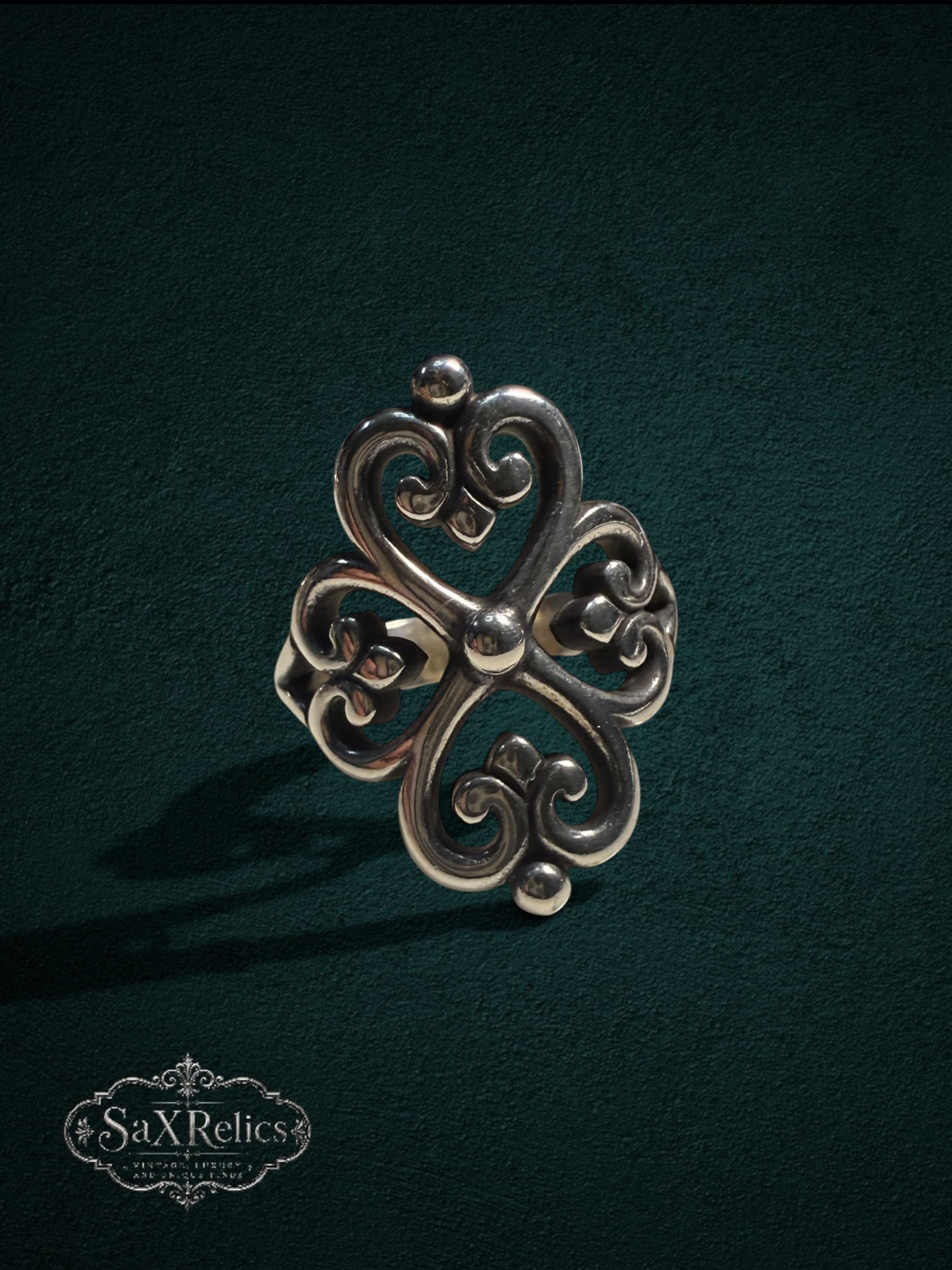 My Store SAXRelics sterling silver ring featuring an ornate quatrefoil filigree design on a dark green background.