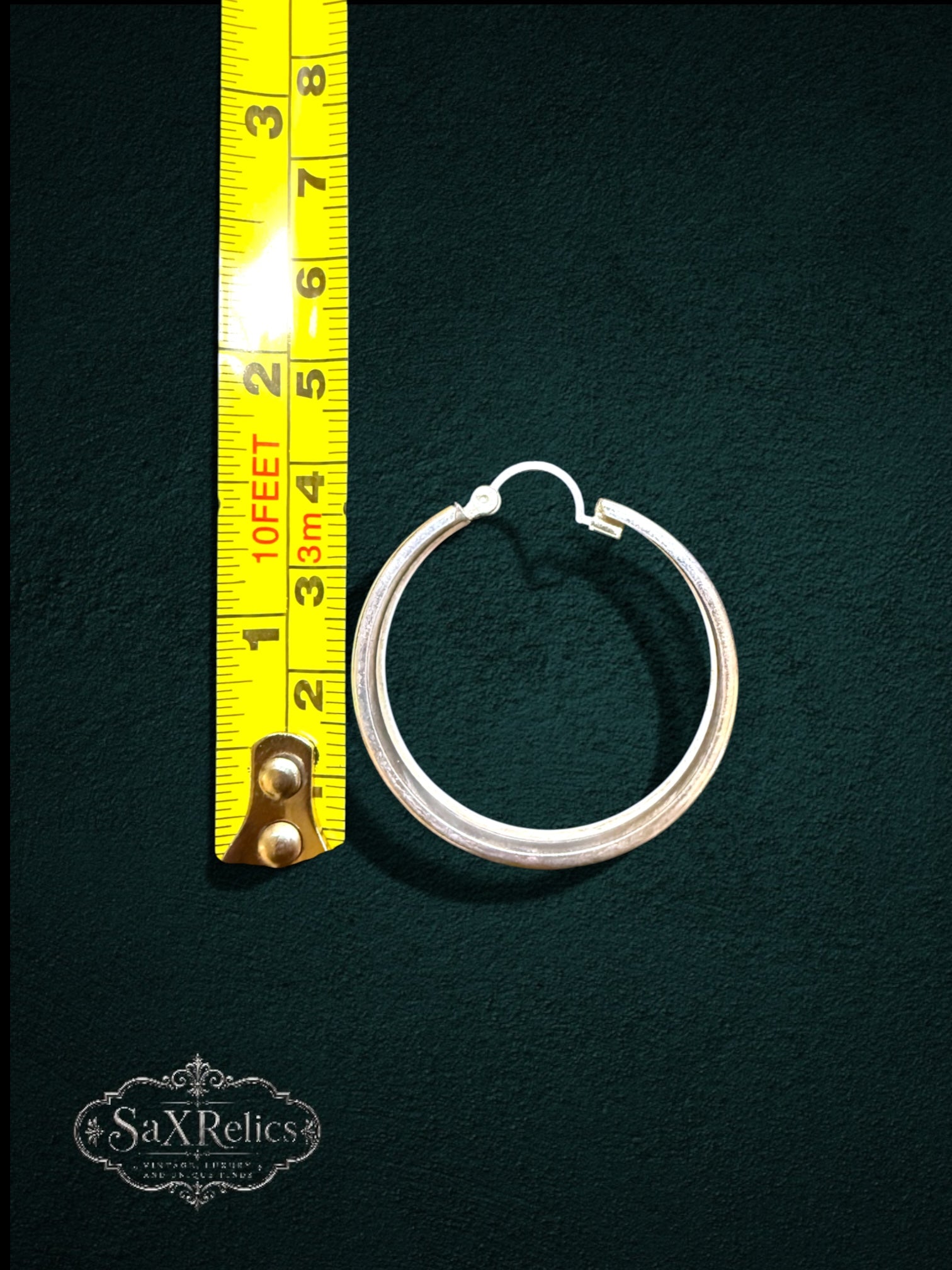 My Store SAXRelics sterling silver hoop earrings with etched design and hinge closure measured against a yellow ruler.