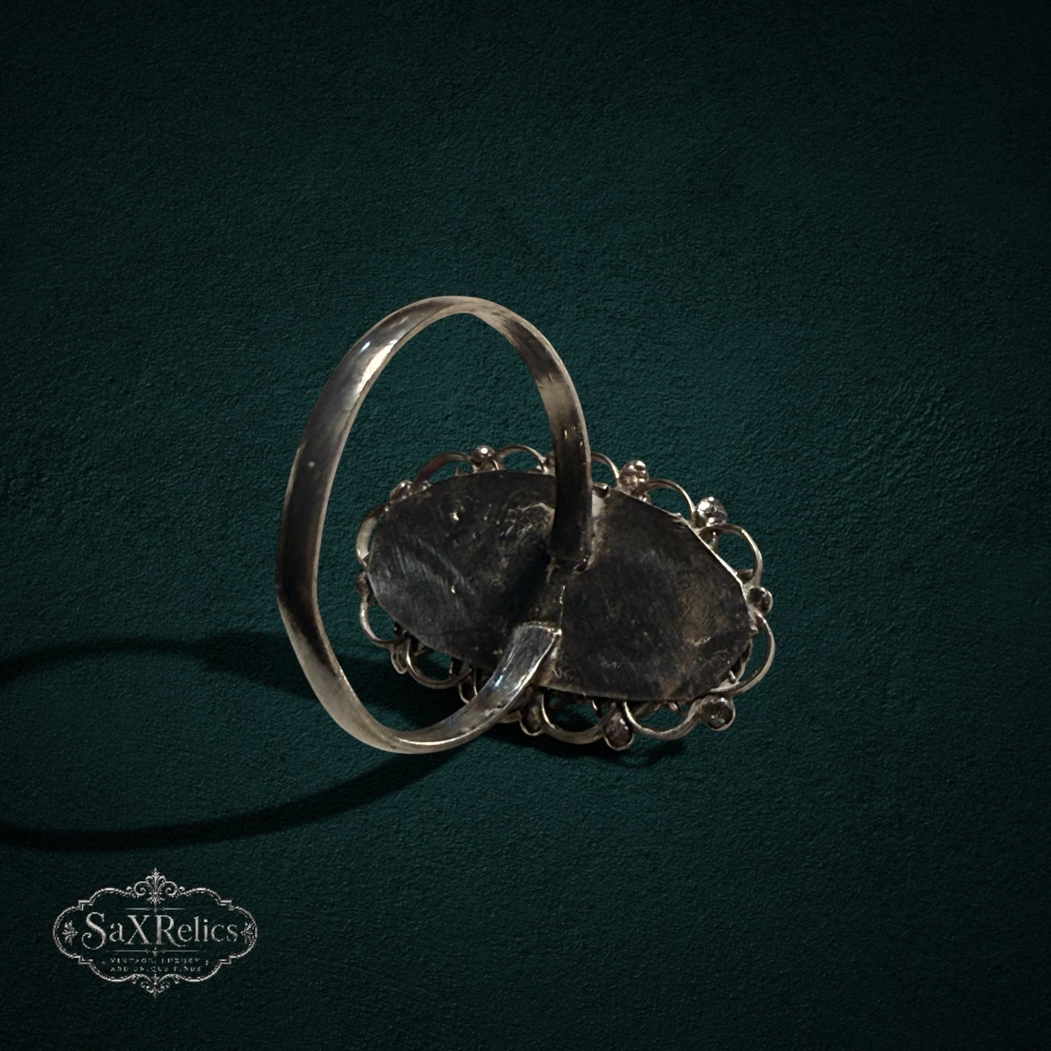 My Store SAXRelics vintage sterling silver ring showing the back of the oval filigree setting on a dark background.