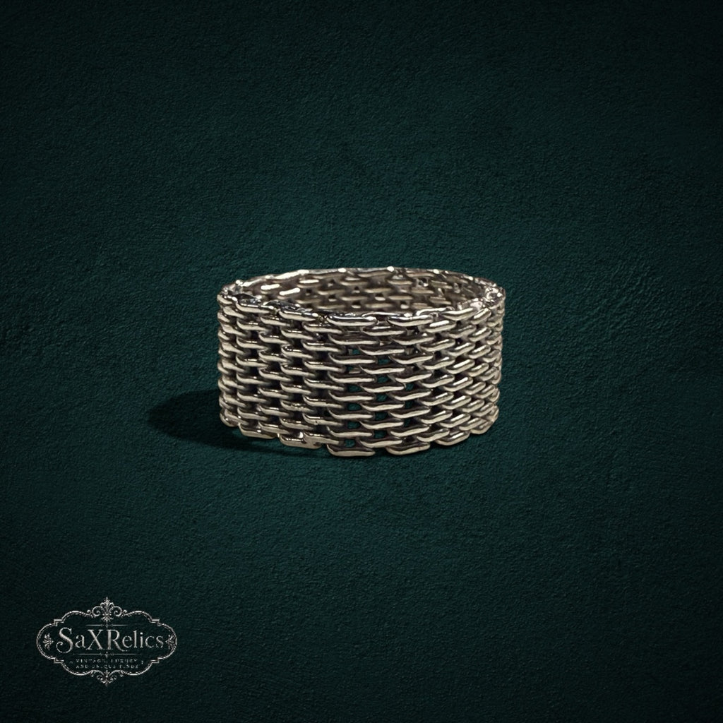 My Store SAXRelics silver-toned woven chain-link band ring with intricate chainmail texture on a dark background.