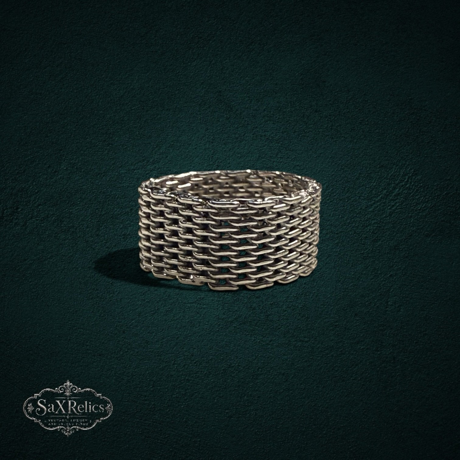 My Store SAXRelics silver-toned woven chain-link band ring with intricate chainmail texture on a dark background.