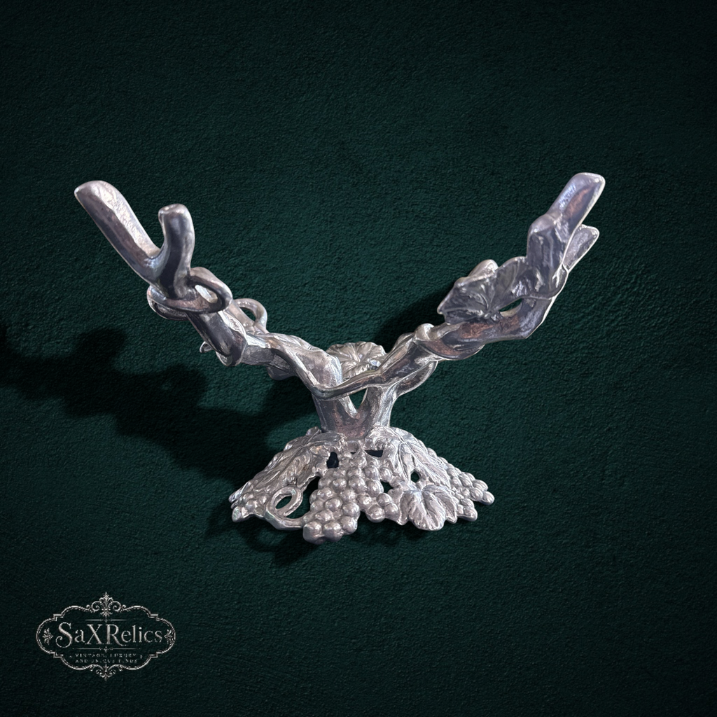 My Store silver metal tabletop display stand featuring an ornate grapevine and leaf motif with four branch-like arms.