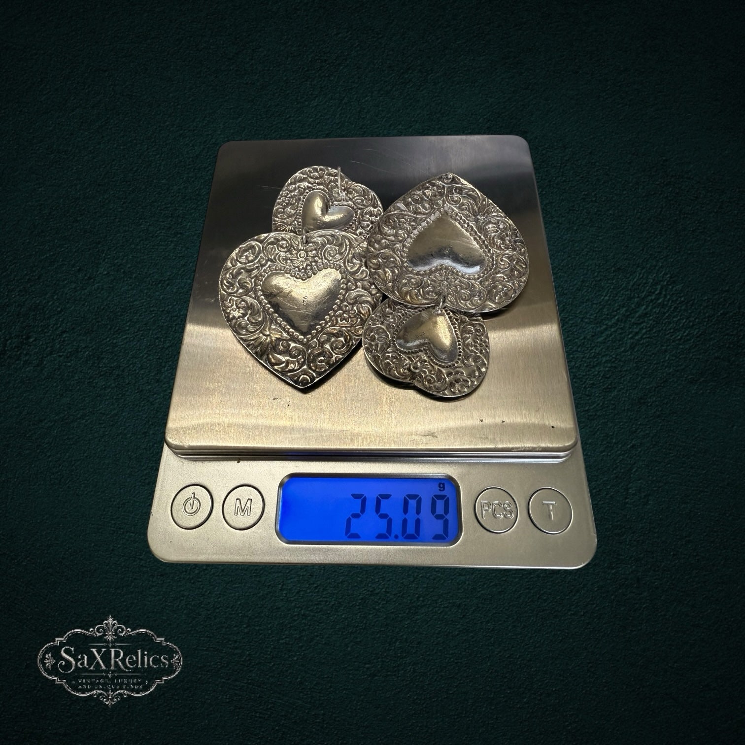 SaX Relics sterling silver 925 heart statement earrings on a digital scale showing 25.09 grams for the pair