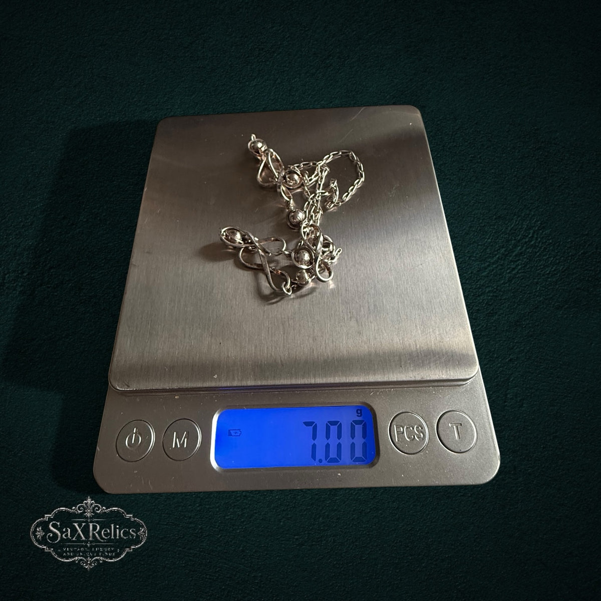 SaX Relics — Infinito sterling silver infinity-link necklace on a digital scale at 7.00 grams.