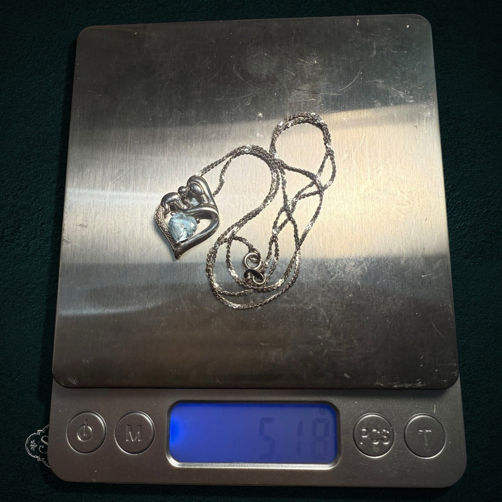 My Store sterling silver mother and child heart pendant necklace with a light blue gemstone on a digital scale