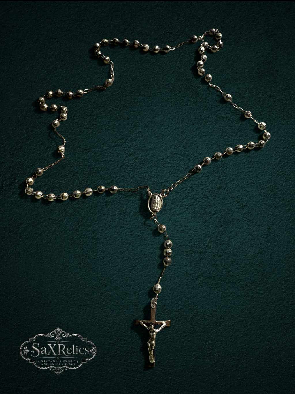 My Store silver-tone rosary necklace with faceted beads, centerpiece medal, and crucifix on a dark green background.