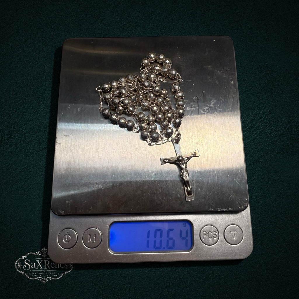 My Store silver-tone rosary beads with a detailed crucifix centerpiece resting on a digital scale weighing 10.64 grams.