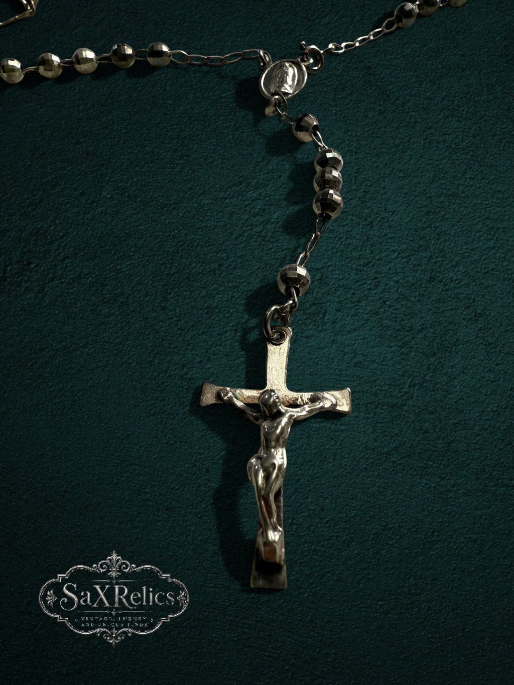 My Store silver-tone religious rosary necklace with faceted beads and a detailed crucifix on a dark green background.