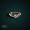 My Store silver-tone solitaire ring with a center stone and shimmering accent stones on a dark green background.