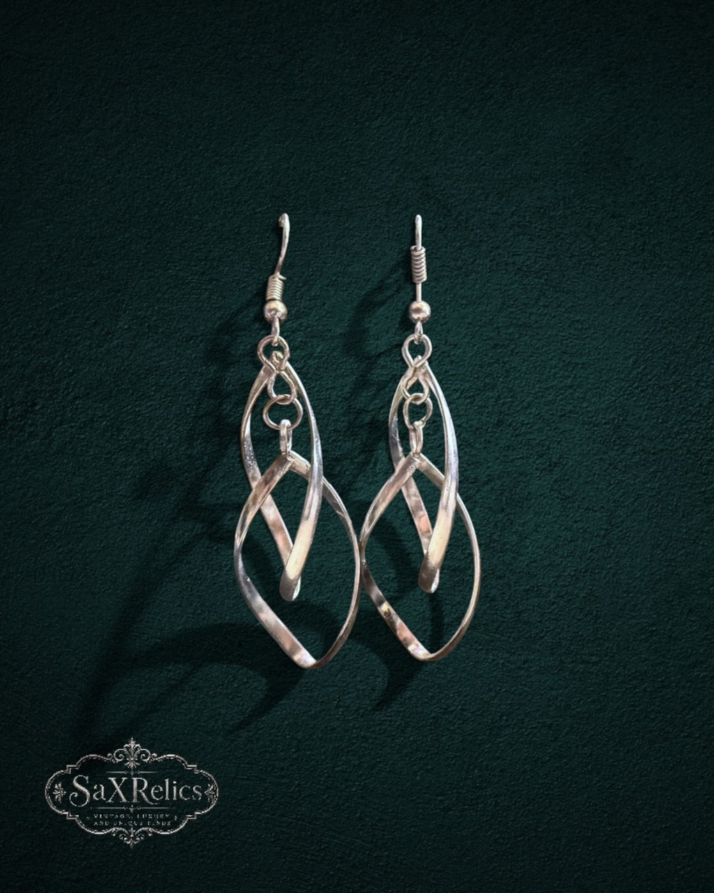 My Store SaxRelics silver-tone intertwined teardrop dangle earrings with a polished finish on a dark background