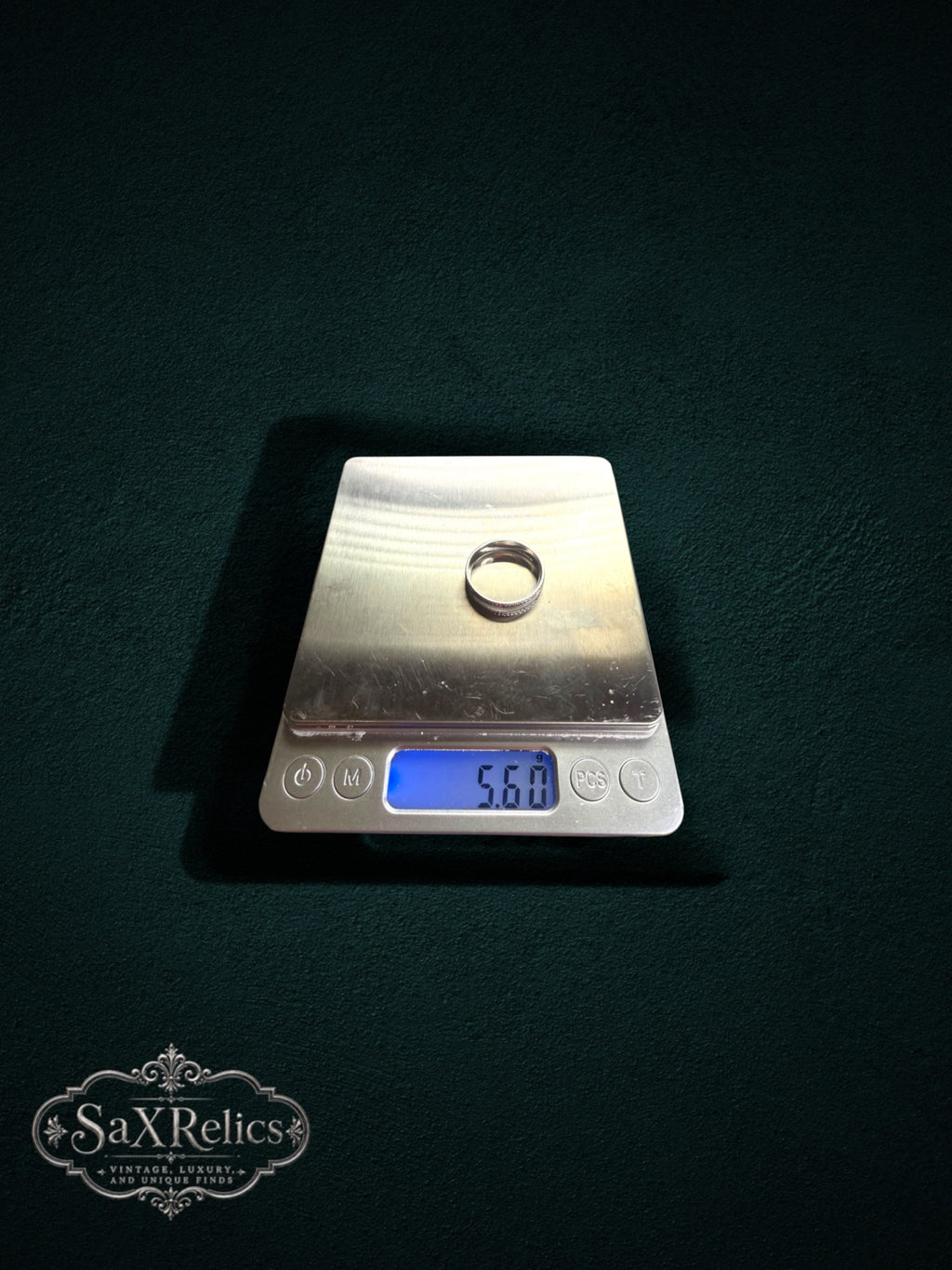 My Store silver band ring with brushed center and beaded edges on a digital scale showing 5.60 grams