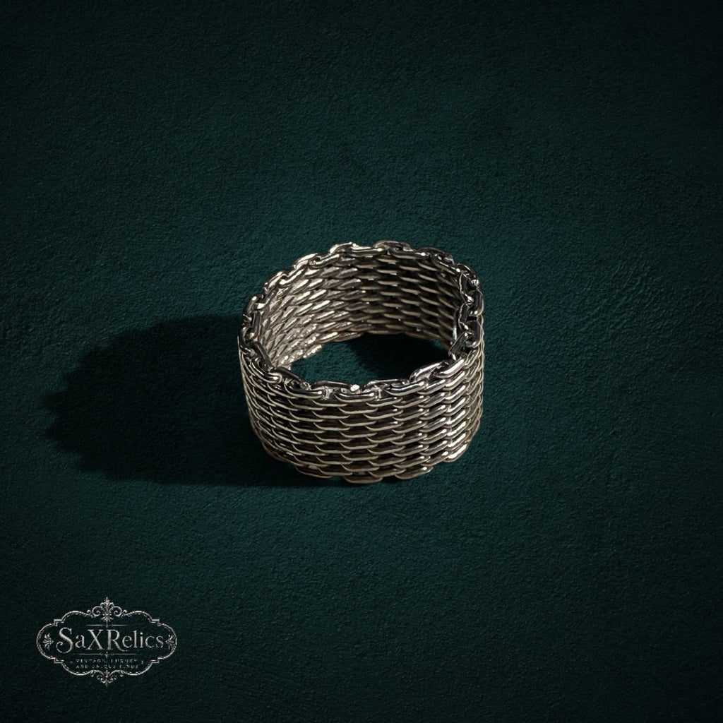 My Store SAXRelics silver-toned woven chain-link band ring with intricate chainmail texture on a dark green background.