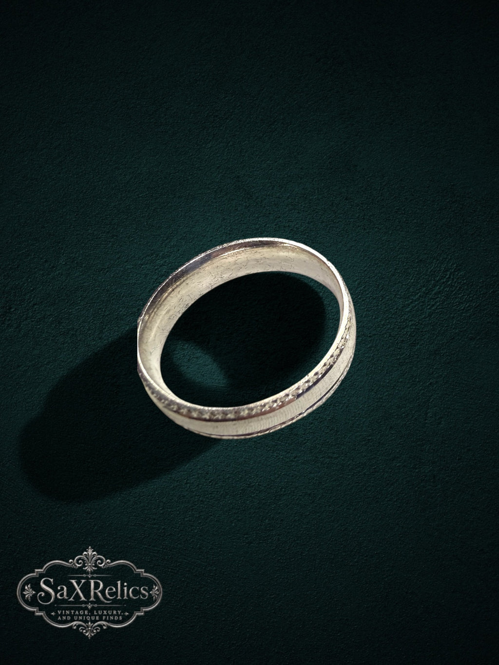 My Store sterling silver band ring with a brushed center and ornate decorative edges on a dark green background.