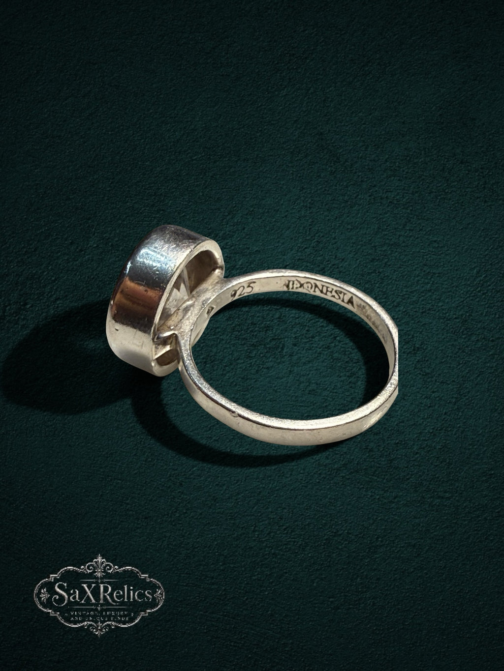My Store SAXRelics 925 sterling silver statement ring with a clear stone and bezel setting on a dark green background.