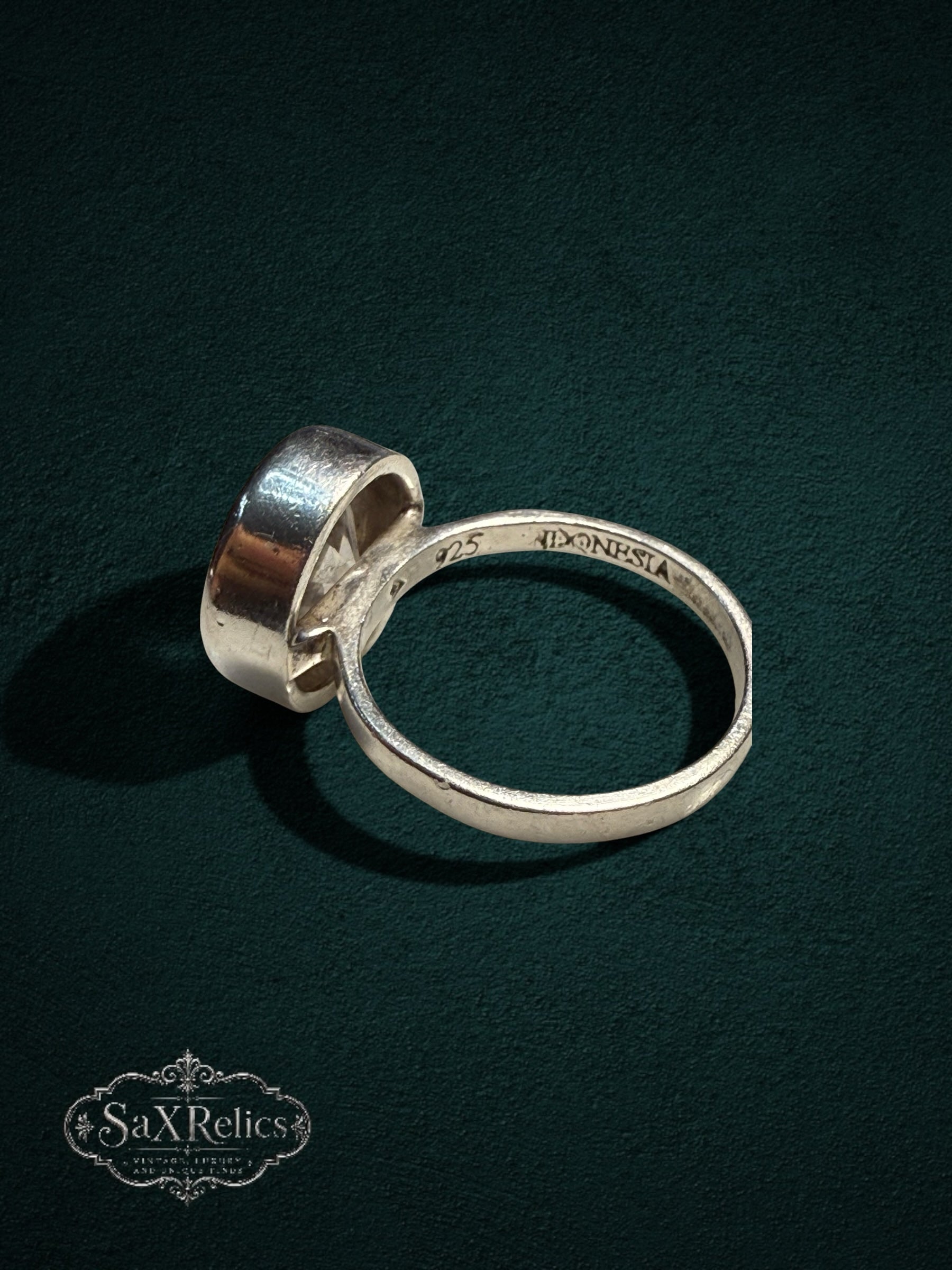 My Store SAXRelics 925 sterling silver statement ring with a clear stone and bezel setting on a dark green background.