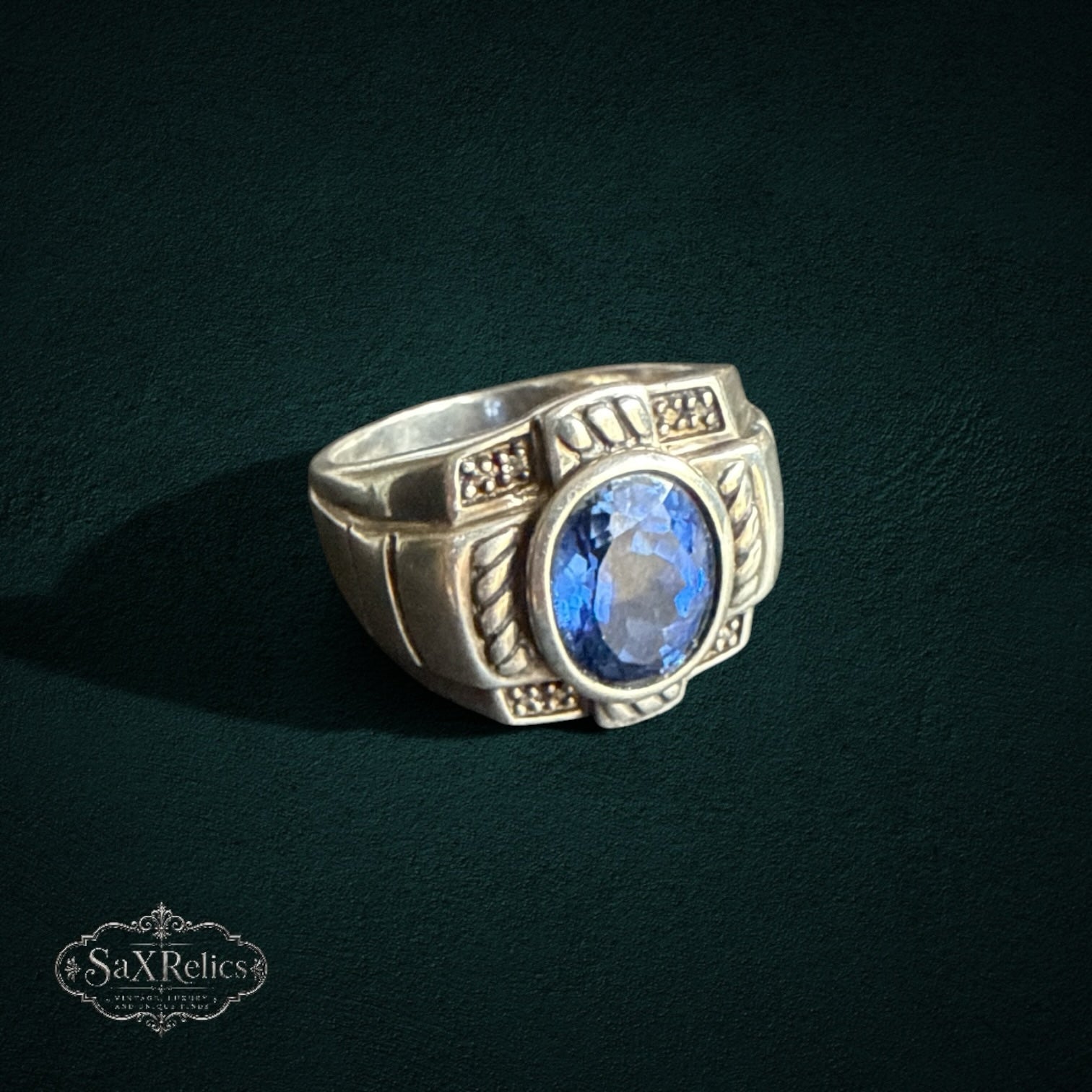 My Store SAXRelics sterling silver statement ring with a deep blue oval gemstone and intricate rope-style detailing.