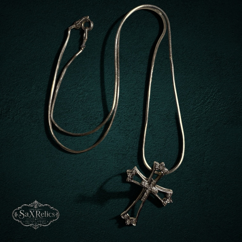 My Store sterling silver cross pendant necklace with clear stones on a sleek snake chain against a dark background.