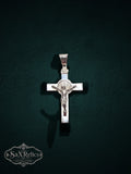 My Store sterling silver crucifix pendant featuring a detailed corpus and Saint Benedict medal on a dark background.