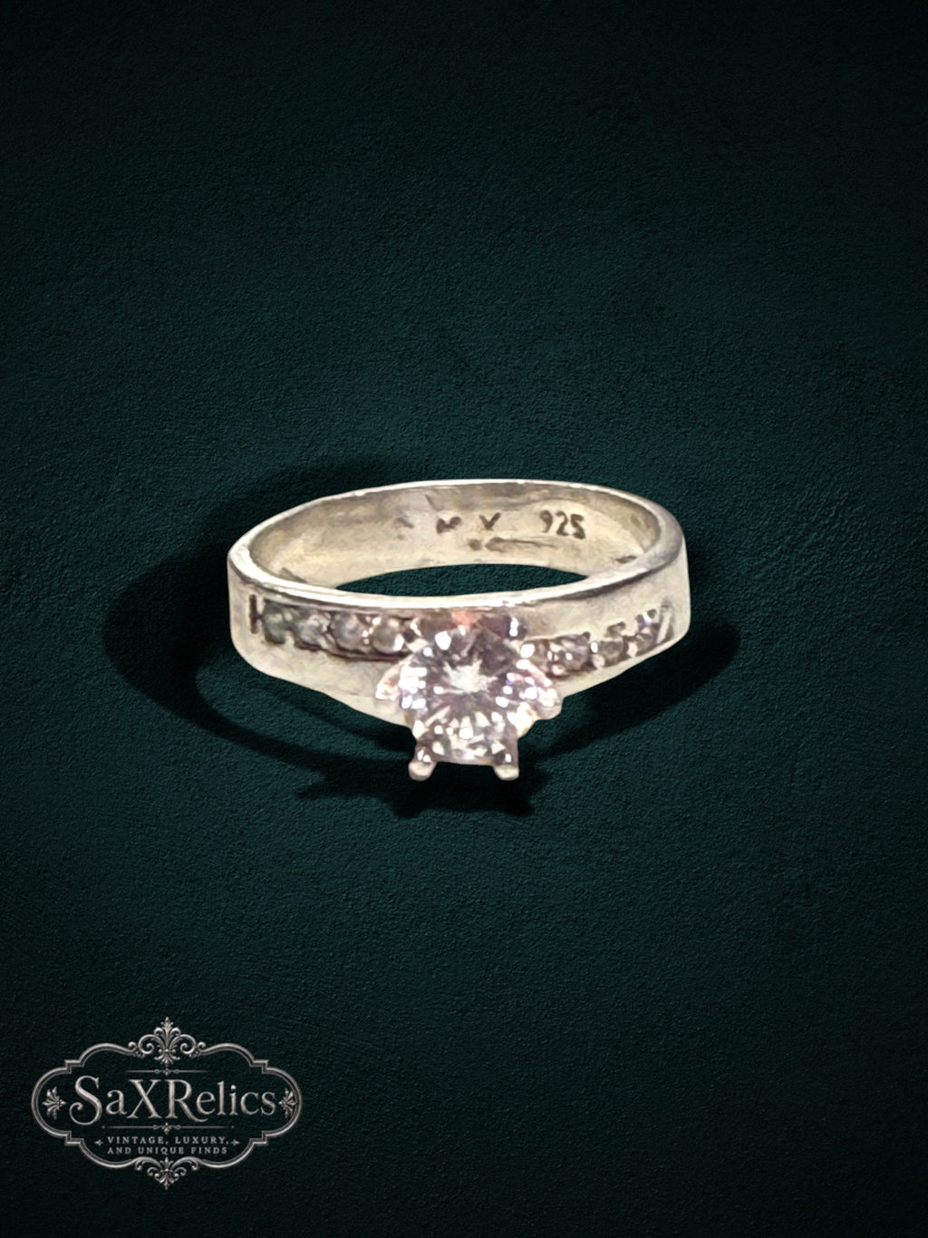 My Store sterling silver engagement ring with a brilliant center stone and channel-set accent stones on a dark background