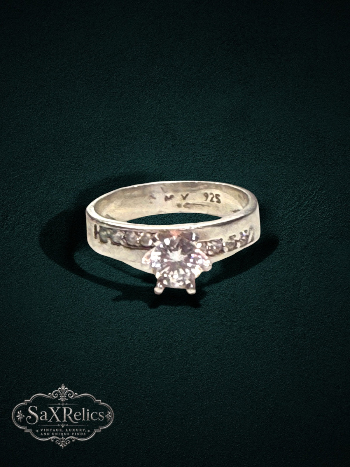 My Store sterling silver engagement ring with a brilliant center stone and channel-set accent stones on a dark background
