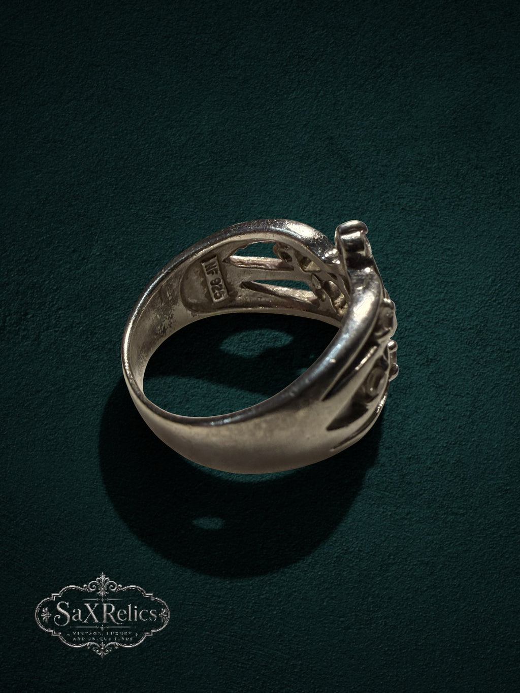 My Store SAXRelics sterling silver statement ring with intricate filigree openwork design on a dark green background.
