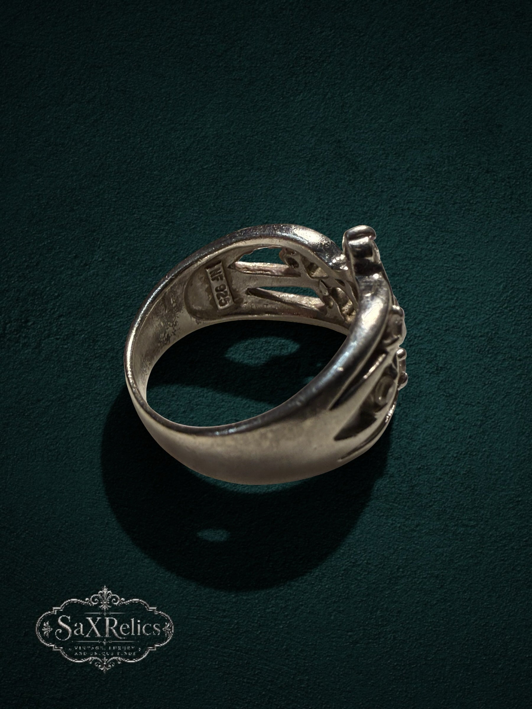 My Store SAXRelics sterling silver statement ring with intricate filigree openwork design on a dark green background.