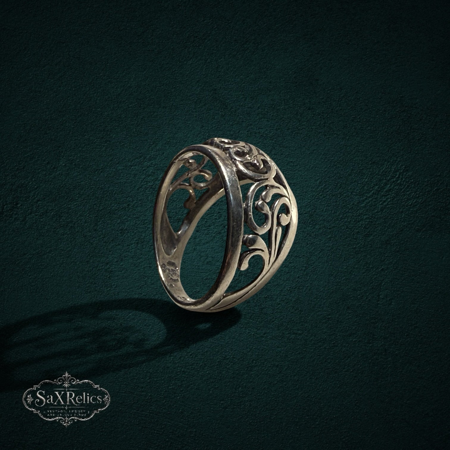 My Store SAXRelics sterling silver ring featuring intricate ornate filigree scrollwork on a dark textured background.