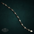 SaX Relics — Delfines sterling silver dolphin-link bracelet, polished links on a dark teal backdrop.