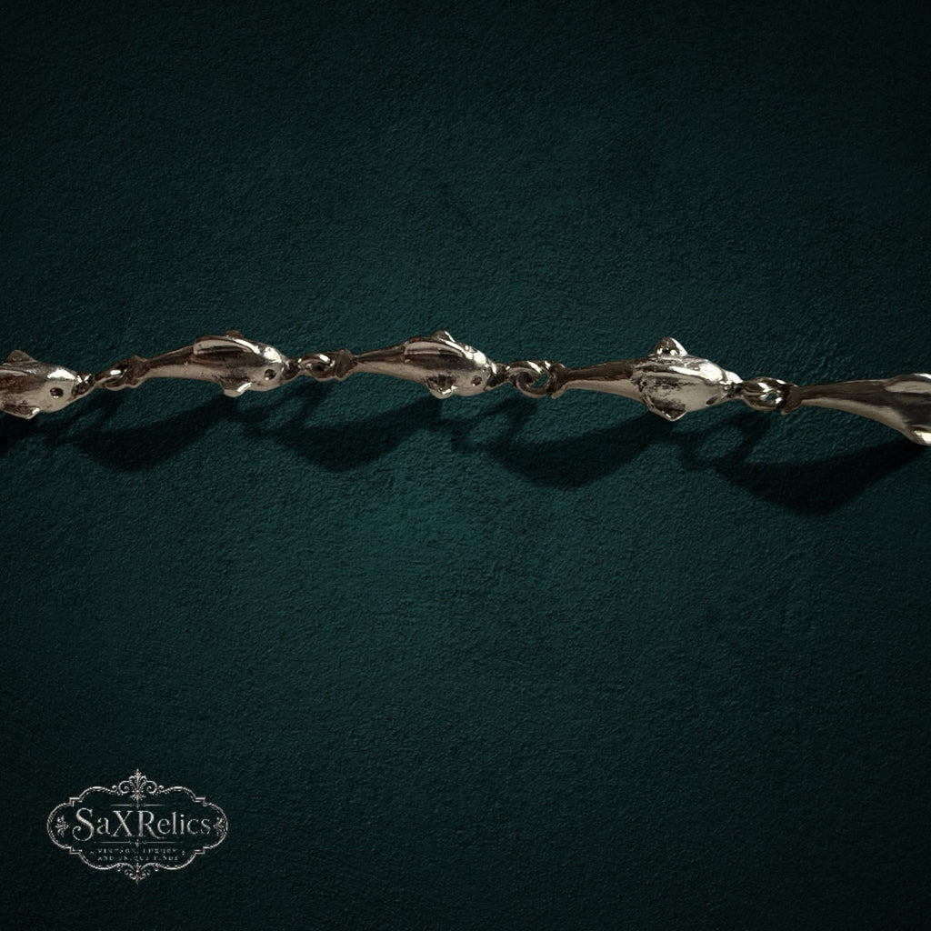 SaX Relics — Delfines sterling silver dolphin-link bracelet, full length shown on a dark teal backdrop.
