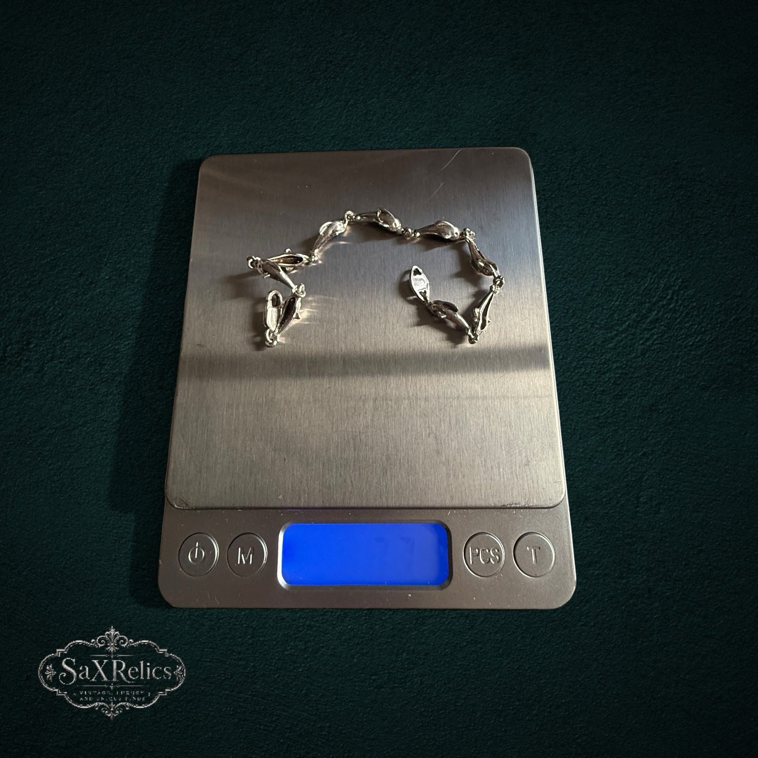 SaX Relics — Delfines sterling silver dolphin-link bracelet on a digital scale at 7.79 grams.