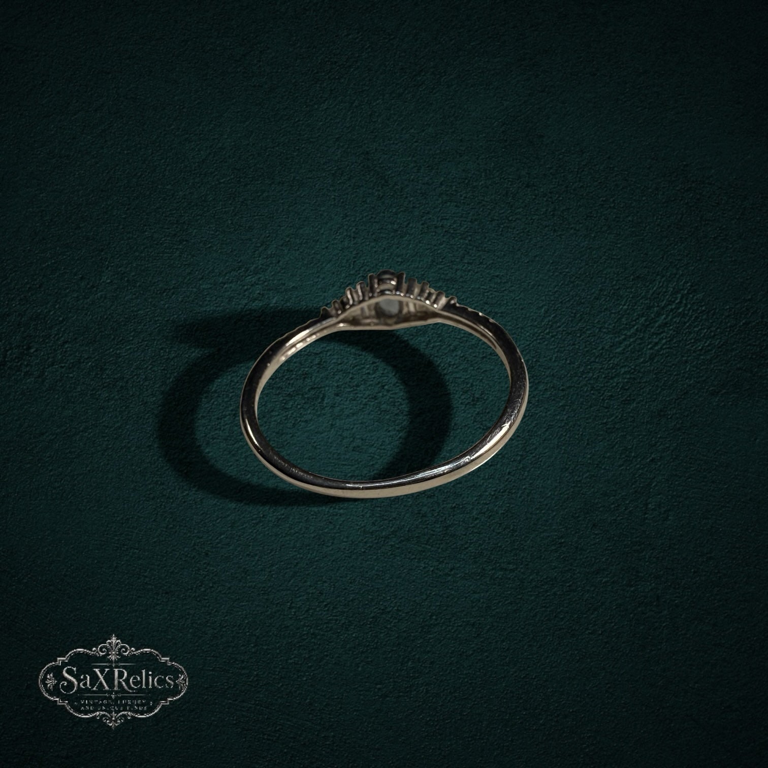 My Store sterling silver ring with central oval gemstone and baguette accents on a dark green background