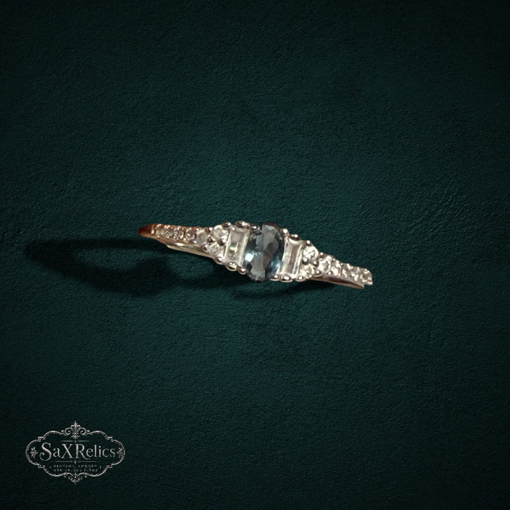 My Store sterling silver ring with a central oval gemstone, baguette accents, and round stones on a dark background.