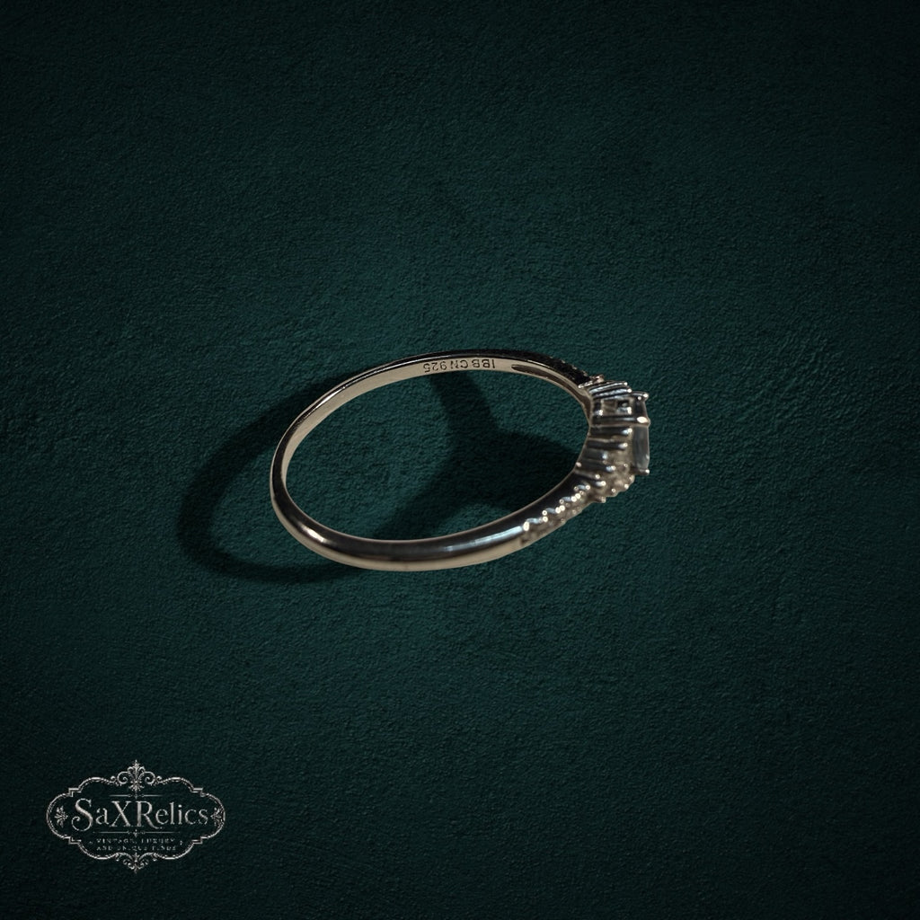My Store sterling silver ring with oval and baguette-cut gemstones on a dark green textured background.