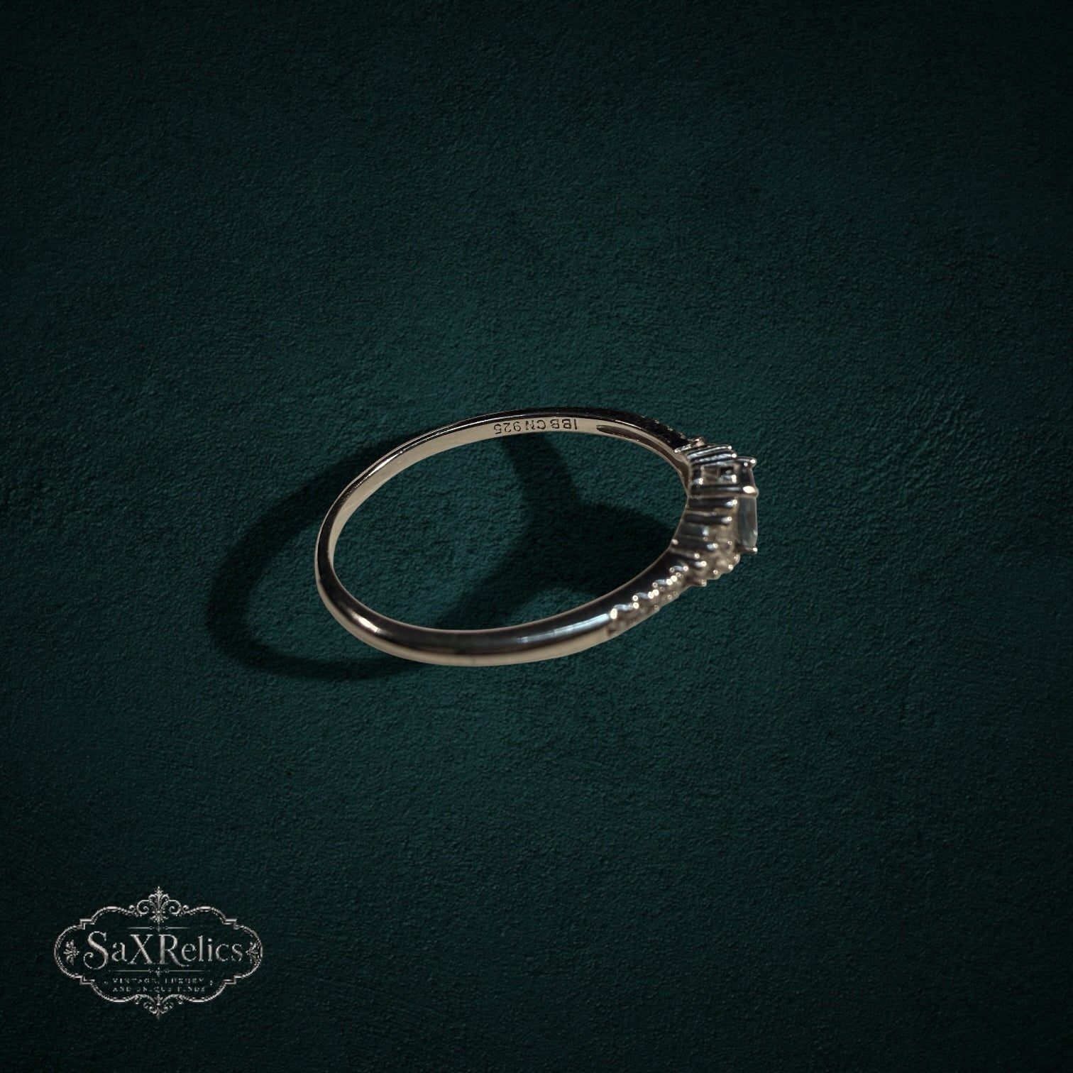 My Store sterling silver ring with oval and baguette-cut gemstones on a dark green textured background.