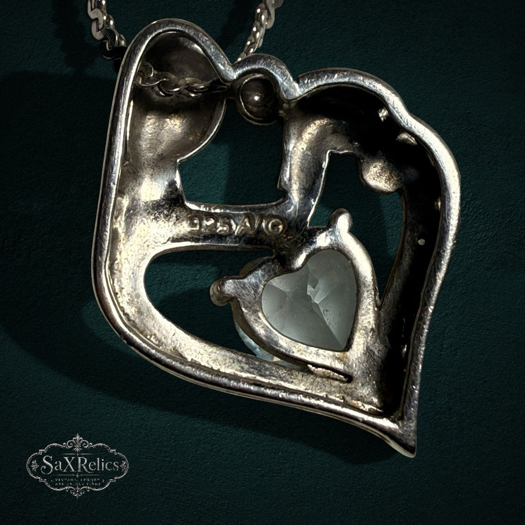 My Store sterling silver mother and child heart pendant necklace with a central light blue heart-cut gemstone.