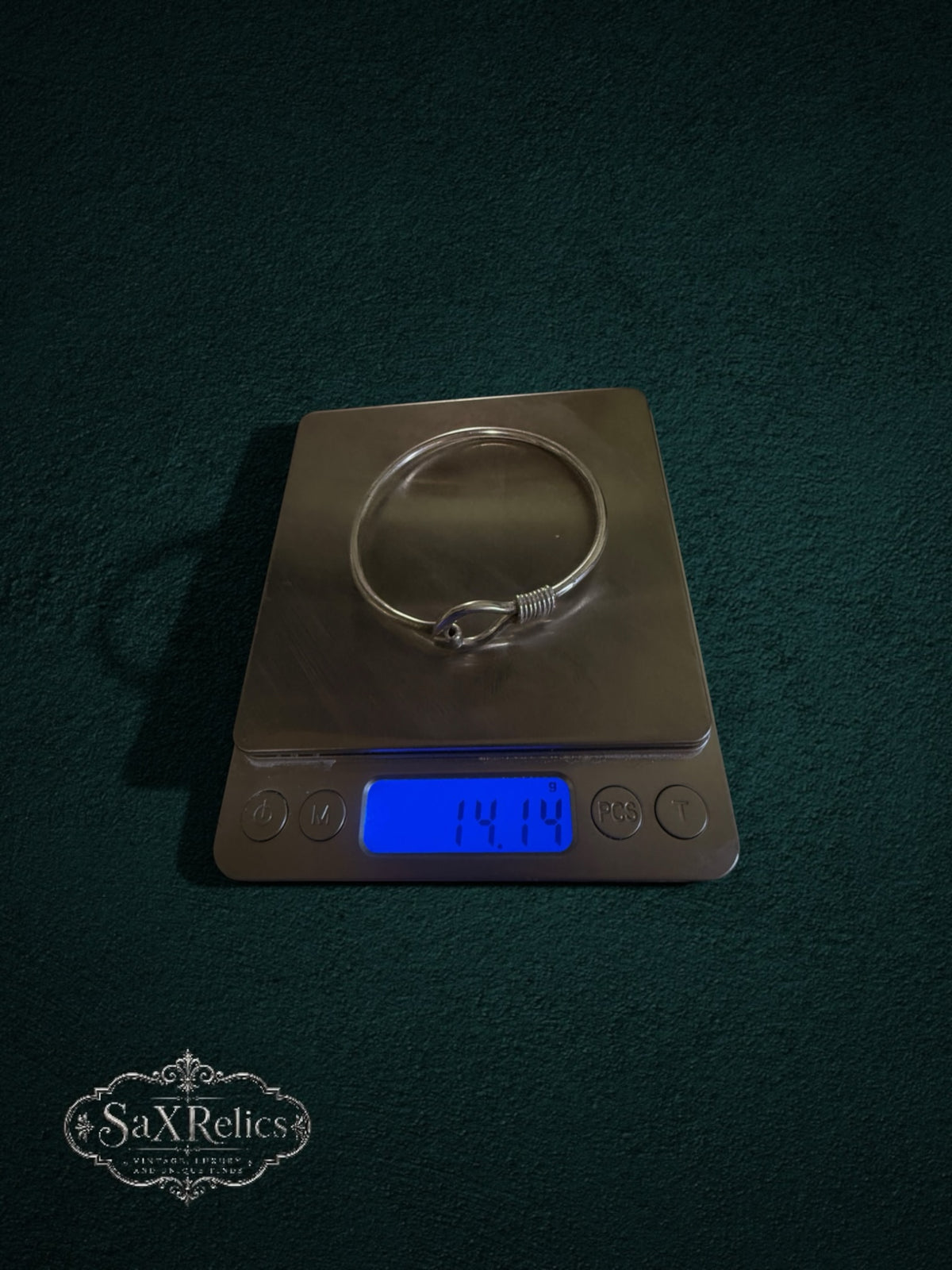 My Store SaxRelics sterling silver hook bangle bracelet on a digital scale showing 14.14 grams