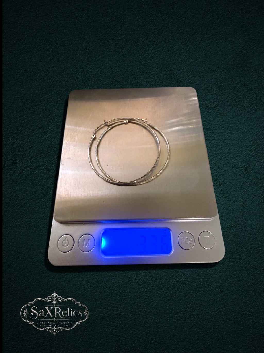 My Store sterling silver hoop earrings with textured finish resting on a digital scale for weight measurement.