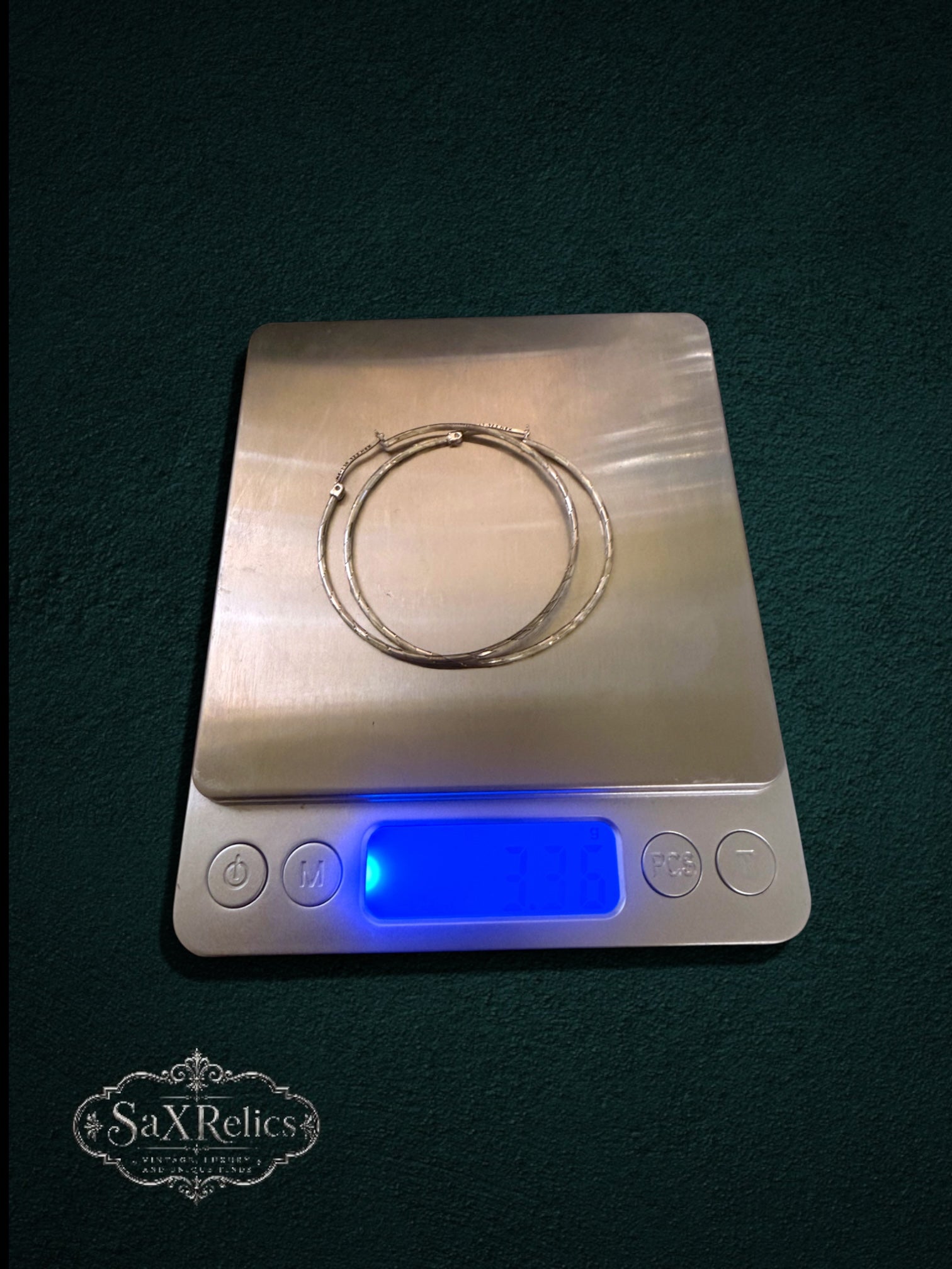My Store sterling silver hoop earrings with textured finish resting on a digital scale for weight measurement.