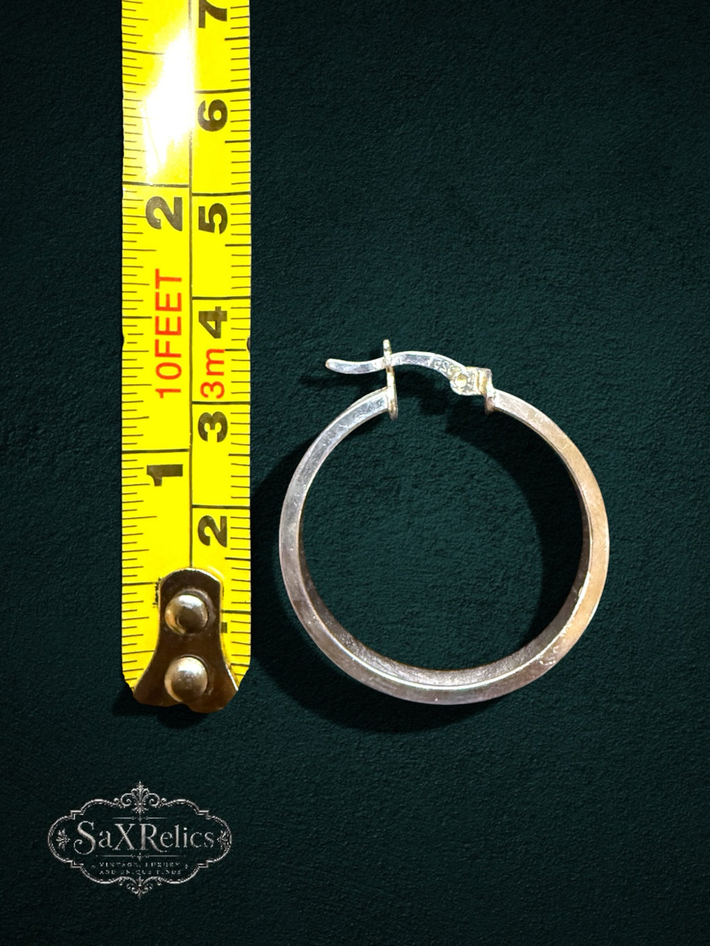 My Store polished sterling silver hoop earrings with engraved circular accents next to a yellow measuring tape.