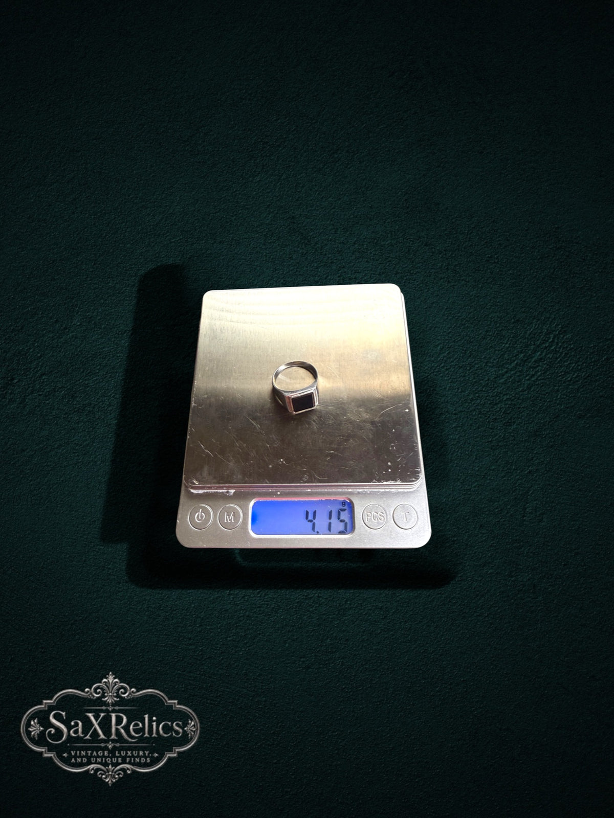 My Store sterling silver rectangular signet ring with black onyx inlay sitting on a digital scale weighing 4.15 grams