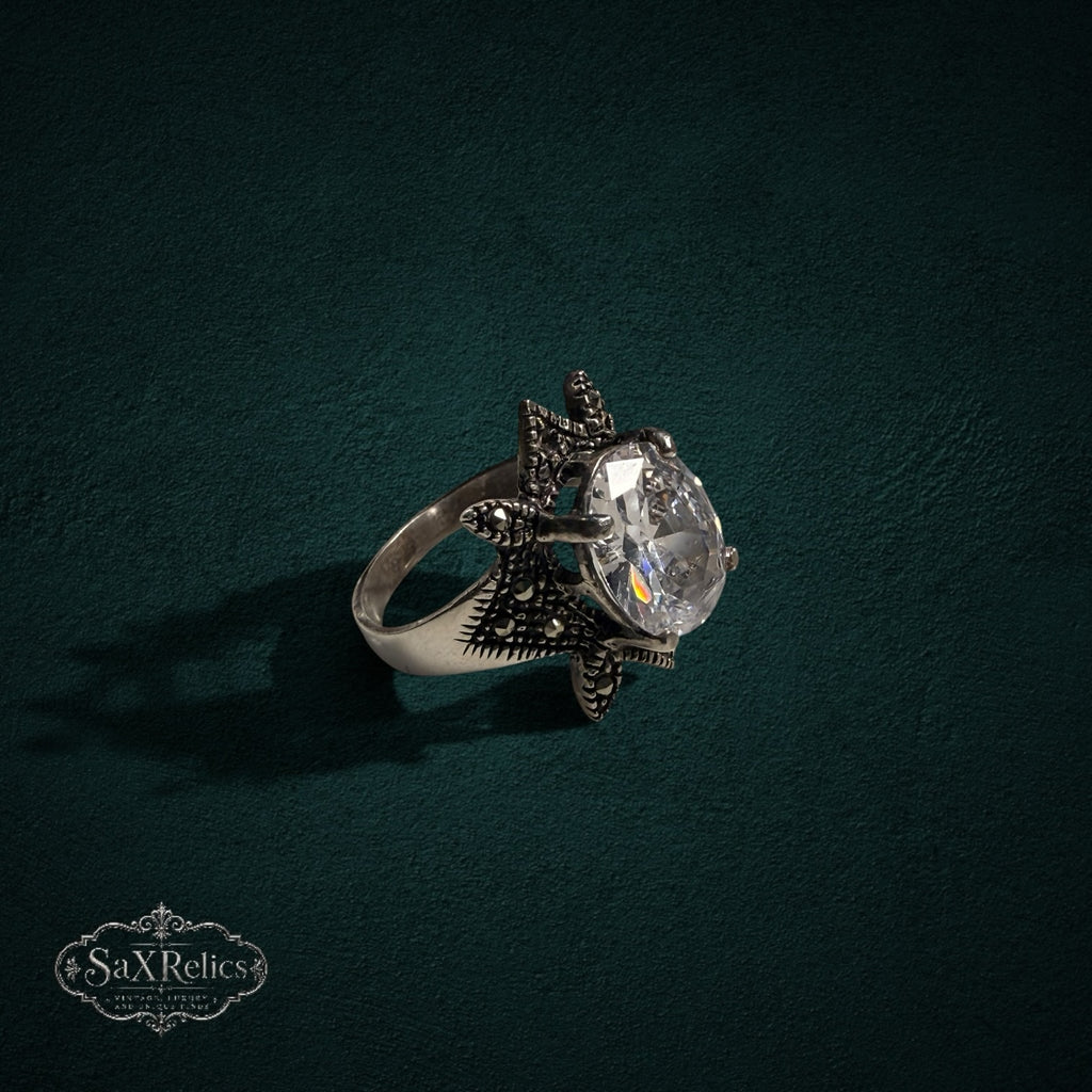My Store SAXRelics sterling silver statement ring with an oval clear stone and star-shaped marcasite setting.