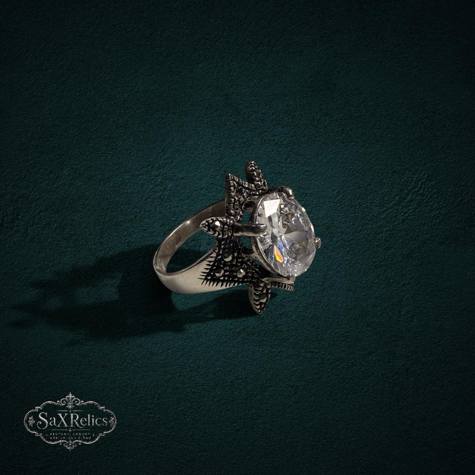 My Store SAXRelics sterling silver statement ring with an oval clear stone and star-shaped marcasite setting.