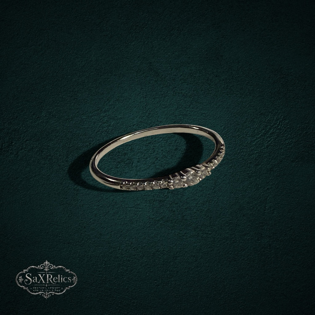 My Store delicate 925 sterling silver band ring featuring a row of shimmering clear stones on a dark green background.