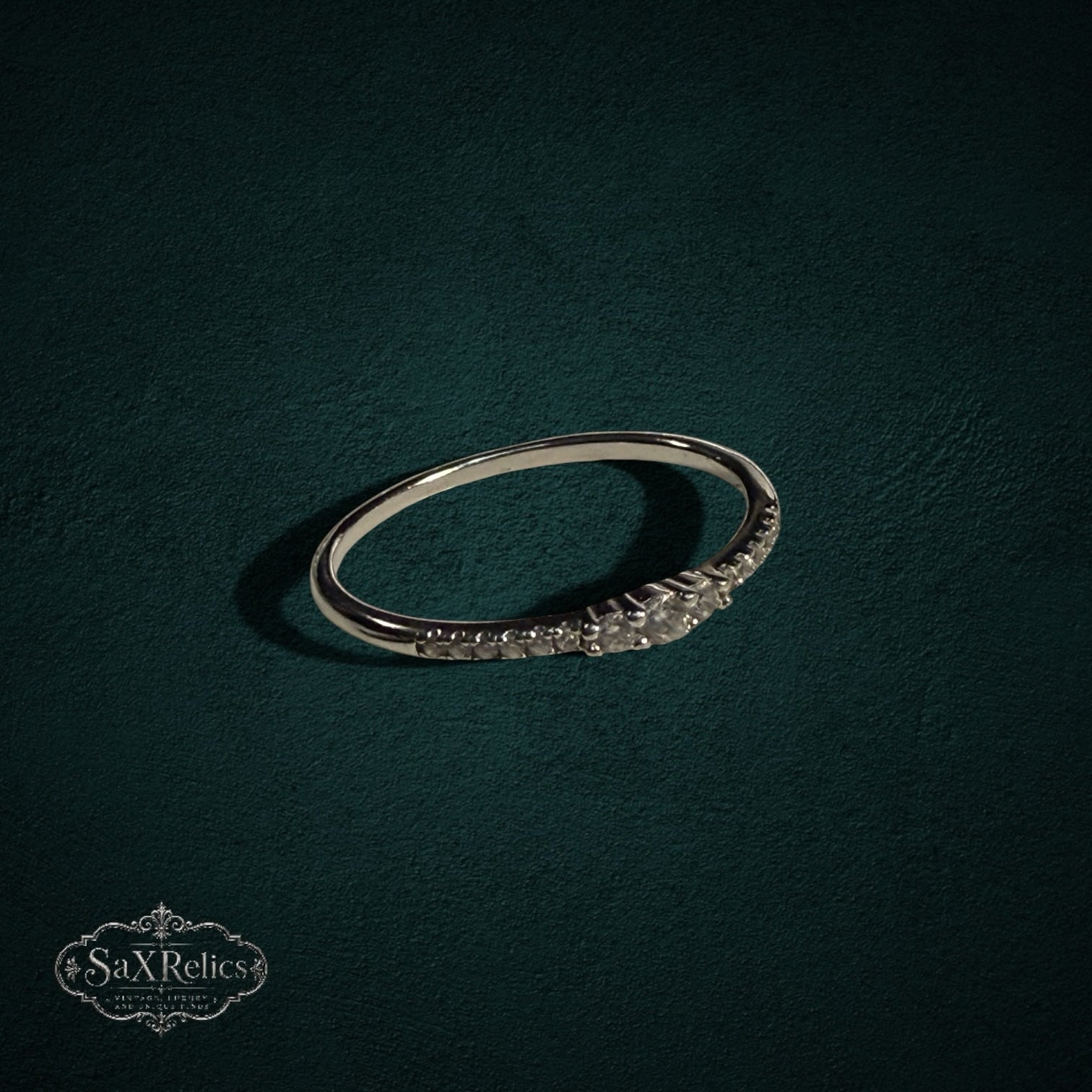 My Store delicate 925 sterling silver band ring featuring a row of shimmering clear stones on a dark green background.